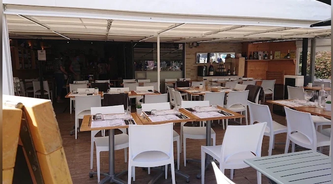 La grande terrasse couverte et ses tables dressées