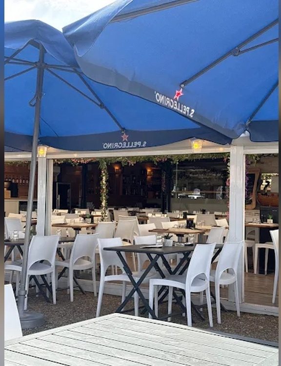 La terrasse extérieure sous les parasols, tables et chaises blanches
